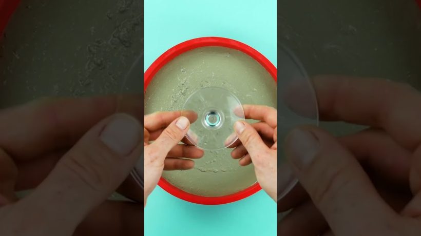 Eine stilvolle Kuchenplatte aus grauem Beton, die auf dem filigranen Stiel eines umgedrehten Weinglases steht.